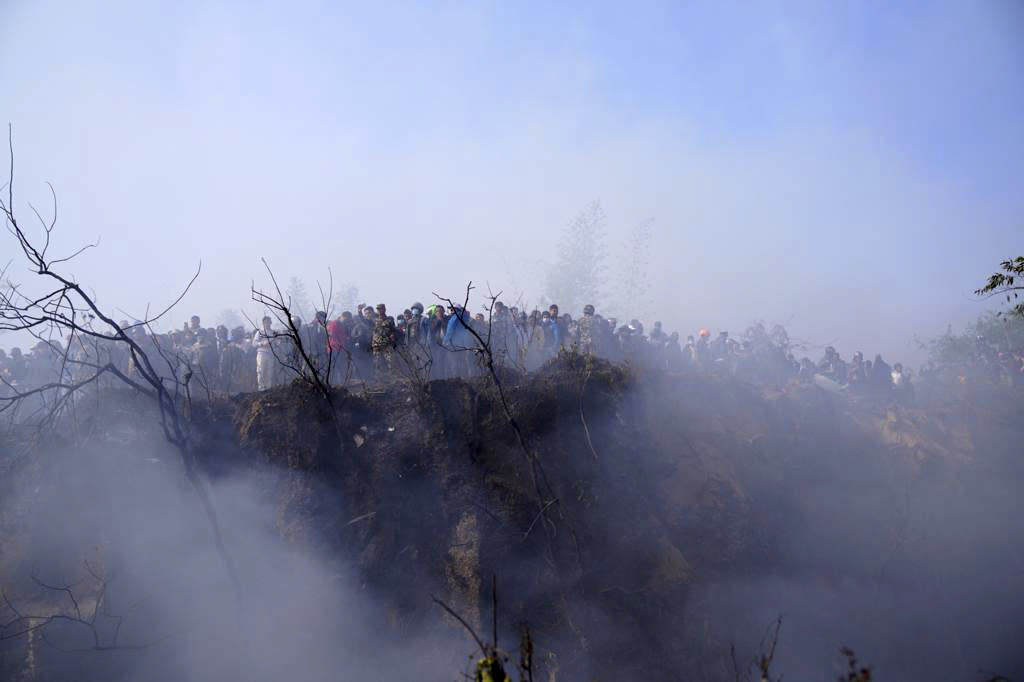 Locals watch the wreckage of a passenger plane in Pokhara, Nepal, Sunday, Jan.15, 2023. A passenger plane with 72 people on board has crashed near Pokhara International Airport in Nepal, the daily newspaper Kathmandu Post reports. The plane was carrying 68 passengers and four crew members. (AP Photo/Yunish Gurung)