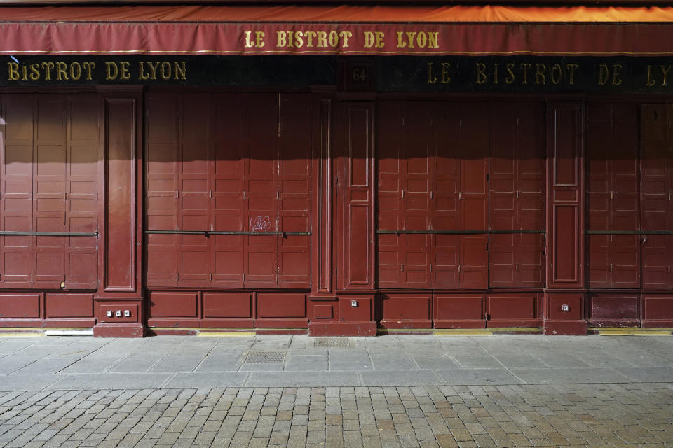 A closed restaurant is pictured after the start of the curfew in the empty center of Lyon, central France, Saturday, Oct. 17, 2020. France is deploying 12,000 police officers to enforce a new curfew that came into effect Friday night for the next month to slow the virus spread, and will spend another 1 billion euros to help businesses hit by the new restrictions. (AP Photo/Laurent Cipriani)