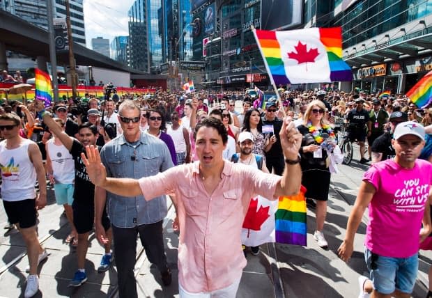 Prime Minister Justin Trudeau waves a flag as he takes part in the annual Pride Parade in Toronto on Sunday, July 3, 2016. The Liberal government continues to promise to end what it's called the "discriminatory" ban on blood donations.