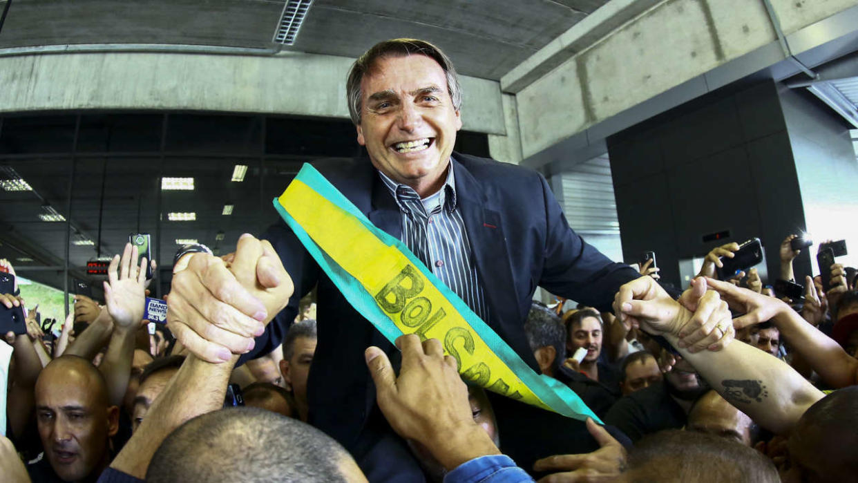 Le député fédéral de droite et candidat à la présidence Jair Bolsonaro, salue les partisans lors d’un rassemblement à l’aéroport Afonso Pena à Curitiba, au Brésil, le 28 mars 2018. - Bolsonaro, qui a fait à plusieurs reprises l’éloge de la dictature militaire brésilienne qui a duré deux décennies, a raillé Lula, le qualifiant de « bandit », et l’a mis au défi à Curitiba de voir « qui peut faire sortir le plus de gens dans la rue sans les payer. » (Photo par Heuler Andrey / AFP)