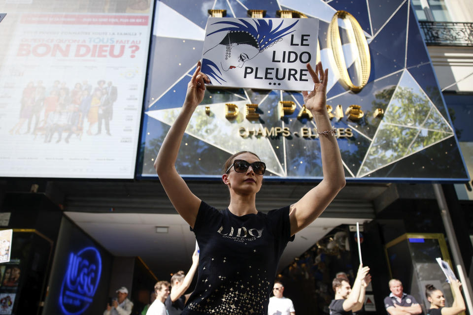 A Lido cabaret employee holds a placard reading "The Lido cries" during a demonstration to try to save jobs and the history of the cabaret, known for its dinner theater and its "Bluebell Girls" revue, Saturday, May 28, 2022 in Paris. Amid financial troubles and changing times, the venue's new corporate owner is ditching most of the Lido's staff and its high-kicking, high-glamour dance shows — which date back decades and inspired copycats from Las Vegas to Beirut — in favor of more modest musical revues. (AP Photo/Thomas Padilla)