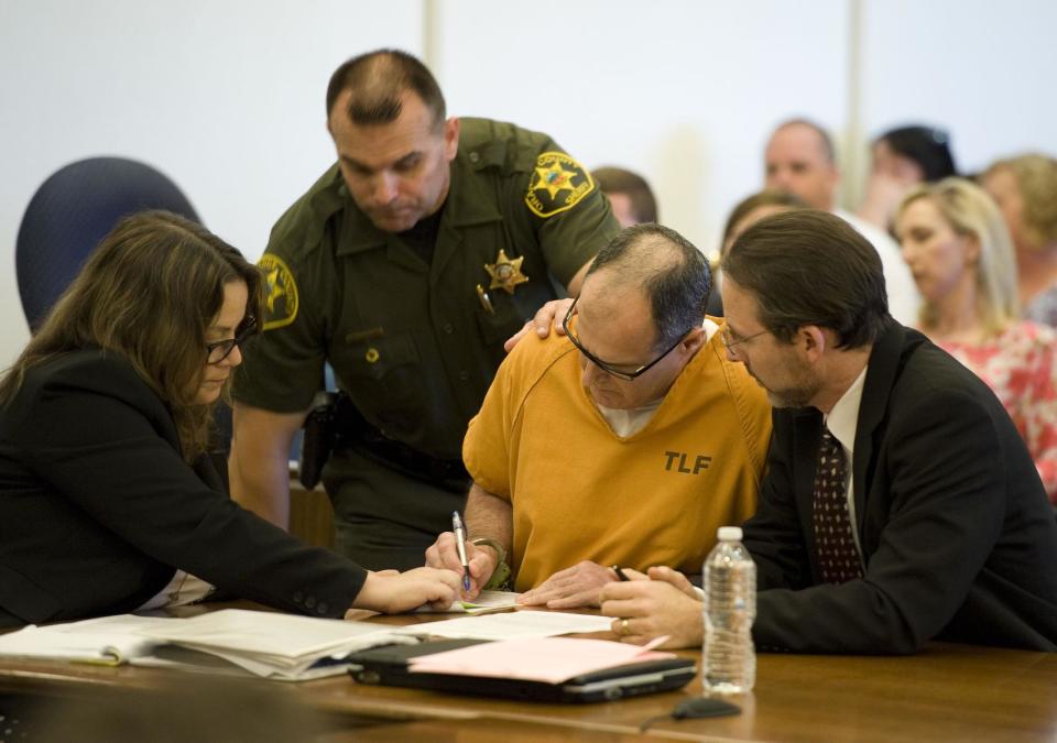 Scott Dekraai signs court documents with his public defenders Lisa Kopelman, left, and Scott Sanders looking on at Orange County Superior Court in Santa Ana, Calif., on Friday, May 2, 2014. Dekraai, 44, who was in a custody fight with his ex-wife pleaded guilty Friday to killing her and seven others in a shooting rampage at a California hair salon in 2011. Dekraai donned a bulletproof vest before heading to the Seal Beach salon where his ex-wife worked as a stylist in October 2011. Authorities said he shot and killed Michelle Fournier before turning his gun on the salon's owner and spraying Salon Meritage with bullets. The salon reopened about a year later, with six of the original employees returning to work. (AP Photo/The Orange County Register, Kevin Sullivan) MAGS OUT; LOS ANGELES TIMES OUT