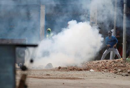 Protesters throw stones amid tear gas smoke fired by police during a protest against the killing of Burhan Wani, a separatist militant leader, in Srinagar, July 10, 2016. REUTERS/Danish Ismail