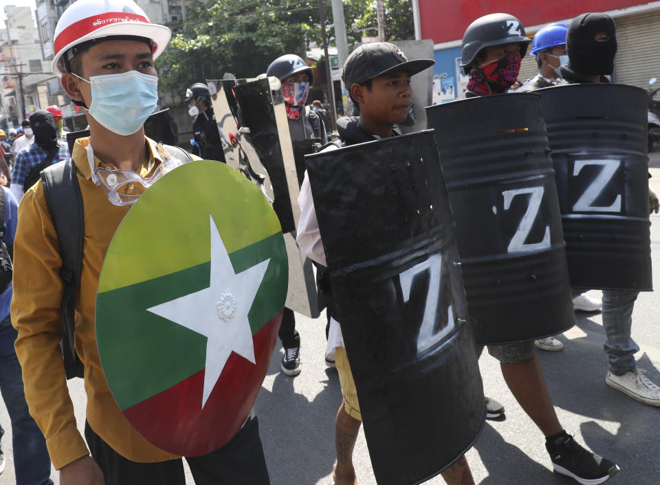 An anti-coup protester holds a round shield with a white star and the colors of the Myanmar flag as he marches with other anti-coup protesters holding shields in Mandalay, Myanmar Friday, Mar. 5, 2021. Demonstrators defy growing violence by security forces and stage more anti-coup protests ahead of a special U.N. Security Council meeting on the country's political crisis. (AP Photo)