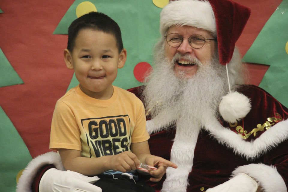 Santa Claus poses with a child at the Trapper School in Nuiqsut, Alaska, on Tuesday, Nov. 29, 2002. Operation Santa Claus, the Alaska National Guard's outreach program, attempts to bring Santa and Mrs. Claus and gifts to children in two or three Alaska Native villages each year, including Nuiqsut in 2022. (AP Photo/Mark Thiessen)