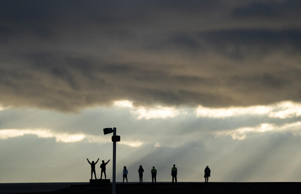 <p>People along Irvine Harbour wall listen to music from one of the speakers on Irvine Beach, on the Ayrshire coast, at the launch the UK premiere of the new public sound installation Signal-On-Sea. Using specially-installed long-throw speakers, the artwork, created by Dutch artists Rob Van Rijswijk and Jeroen Strijbos, connects land and sea with music. Picture date: Wednesday July 14, 2021.</p>
