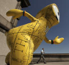 A man walks past an Olympic mascot statue painted in the likeness of a map Monday, July 23, 2012, in London. The statue is one of 84 fiberglass sculptures of the mascots Wenlock or Mandeville that were painted by various artists and erected across the city for the 2012 London Olympic Games. (AP Photo/Charlie Riedel)