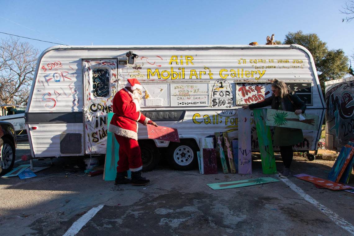 Paige Stiles looks at paintings by Ernest Lee, more commonly known as the Chicken Man, at his corner of Gervais Street on Friday, December 15, 2022. Stiles is shopping for gifts for friends and a new painting for herself.