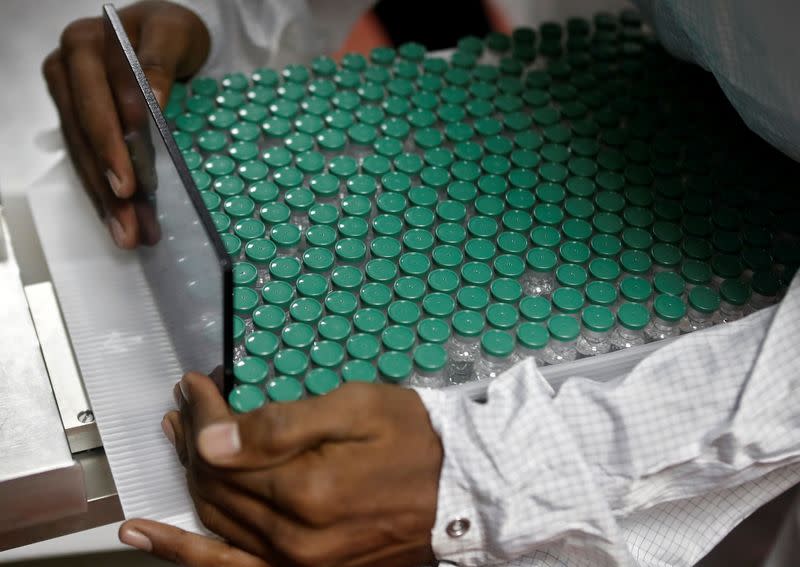 An employee in personal protective equipment (PPE) removes vials of AstraZeneca's COVISHIELD, coronavirus disease (COVID-19) vaccine from a visual inspection machine inside a lab at Serum Institute of India, in Pune
