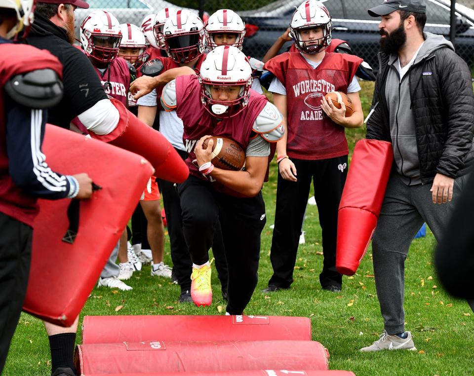 Worcester Academy's Tucker Welcom of Holden runs a gauntlet of fellow players and coaches wielding pads during practice.