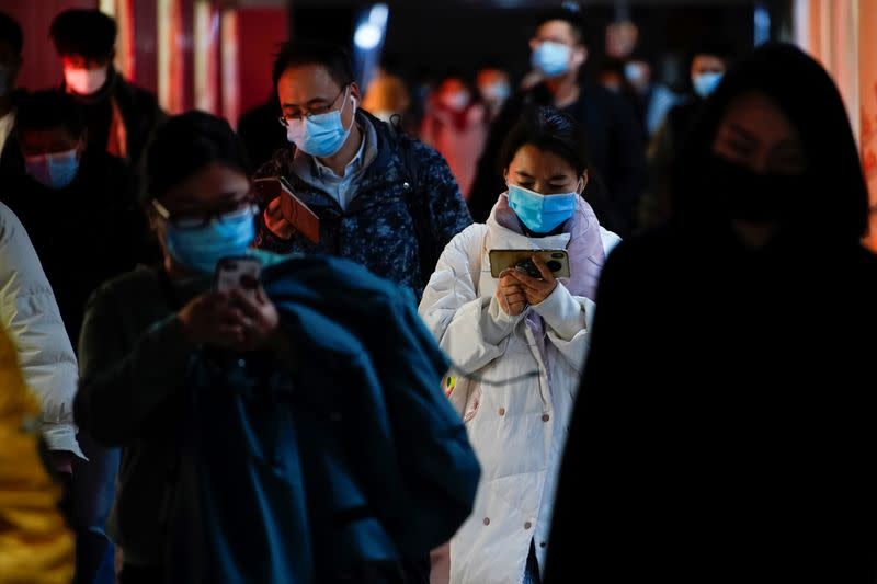 People wearing face masks use their cellphones at a subway station following the coronavirus disease (COVID-19) outbreak, in Shanghai