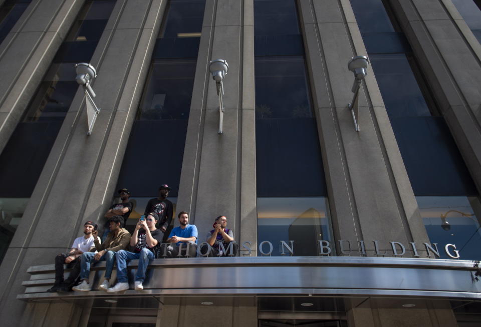 Toronto Raptors fans sit on a building sign during the Toronto Raptors NBA basketball championship parade in Toronto, Monday, June 17, 2019. (Andrew Lahodynskyj/The Canadian Press via AP)