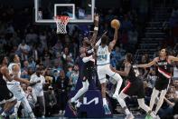 Charlotte Hornets forward Brandon Miller (24) drives to the basket while guarded by Portland Trail Blazers center Deandre Ayton (2) during the second half of an NBA basketball game Wednesday, April 3, 2024, in Charlotte, N.C. (AP Photo/Jacob Kupferman)
