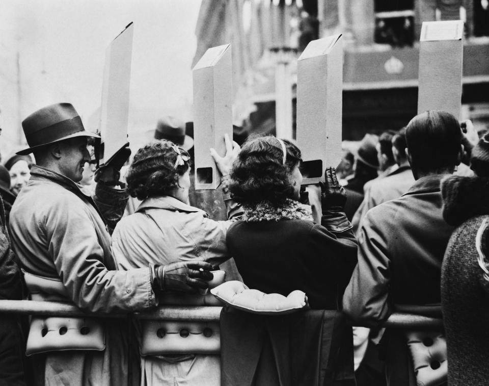 People in the crowd use cardboard periscopes to catch a glimpse of the Gold State Coach en route to the coronation ceremony on May 12, 1937.<span class="copyright">Becker/Fox Photos/Hulton Archive/Getty Images</span>