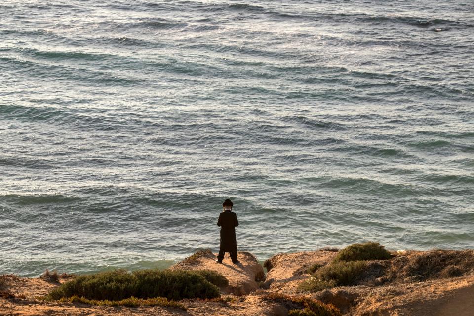 A man prays along the Mediterranean Sea