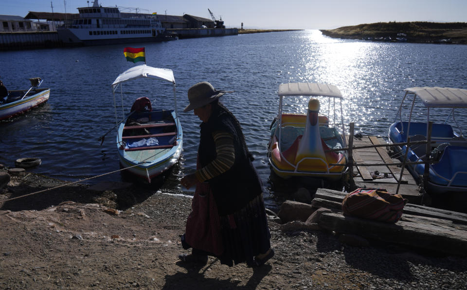 Una mujer aymara camina junto a la orilla del lago Titicaca, en el puerto de Guaqui, Bolivia, el 27 de julio de 2023. El bajo nivel del agua en el lago está teniendo un impacto directo en la flora y la fauna locales y afecta a las comunidades locales que dependen de la frontera natural entre Perú y Bolivia para su sustento. (AP Foto/Juan Karita)