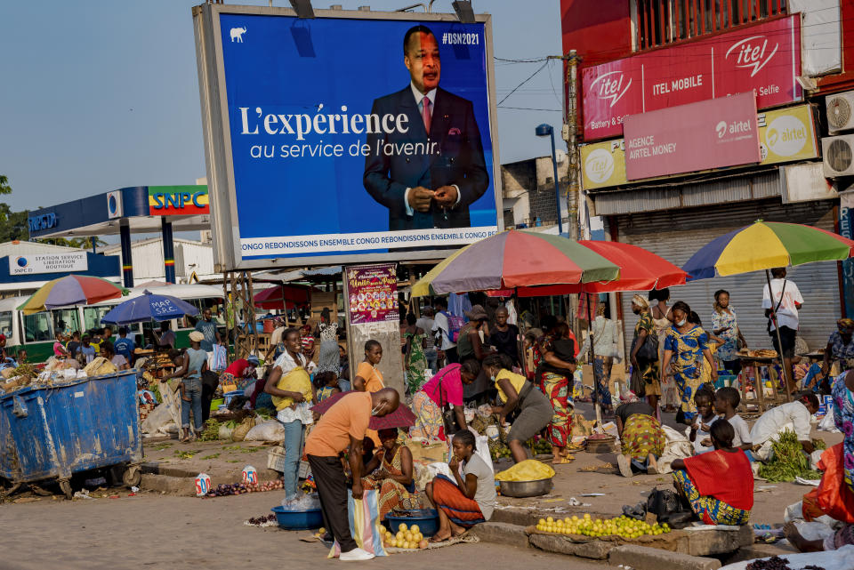 An election poster featuring President Denis Sassou N'Guesso stands over a market in central Brazzaville, Congo, Sunday March 7, 2021. Elections on Sunday March 21 will see President Denis Sassou N'Guesso poised to extend his tenure as one of Africa's longest serving leaders, 36 years, amid opposition complaints of interference with their campaigns. (AP Photo/Lebon Chansard Ziavoula)