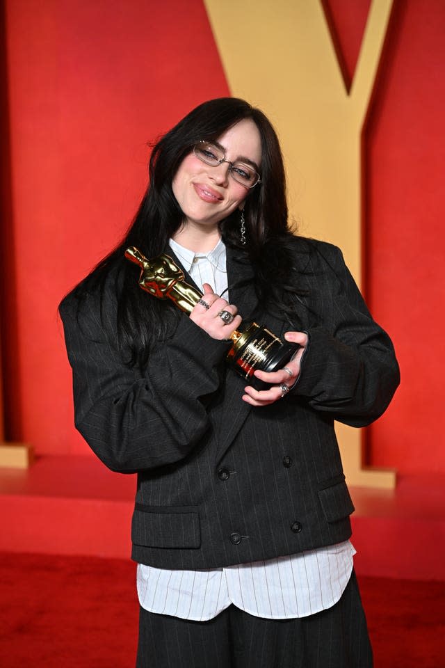 A woman in a black jacket holds an Oscar statuette