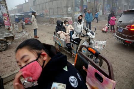 People wear face masks as heavy smog blankets Shenfang in Hebei province, on an very polluted day December 20, 2016. REUTERS/Damir Sagolj