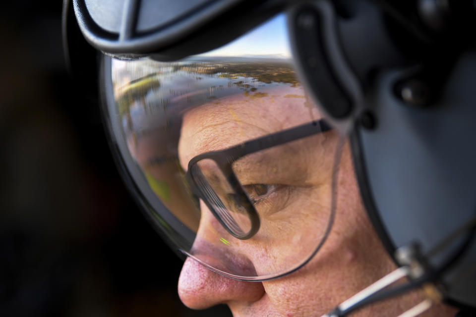 Flood affected areas are reflected in the visor of Australia's Prime Minister Scott Morrison as he surveys flooded areas in Windsor, northwest of Sydney, by air Wednesday, March 24, 2021. Some 18,000 residents of Australia's most populous state have fled their homes since last week, with warnings the flood cleanup could stretch into April. (Lukas Coch/Pool Photo via AP)