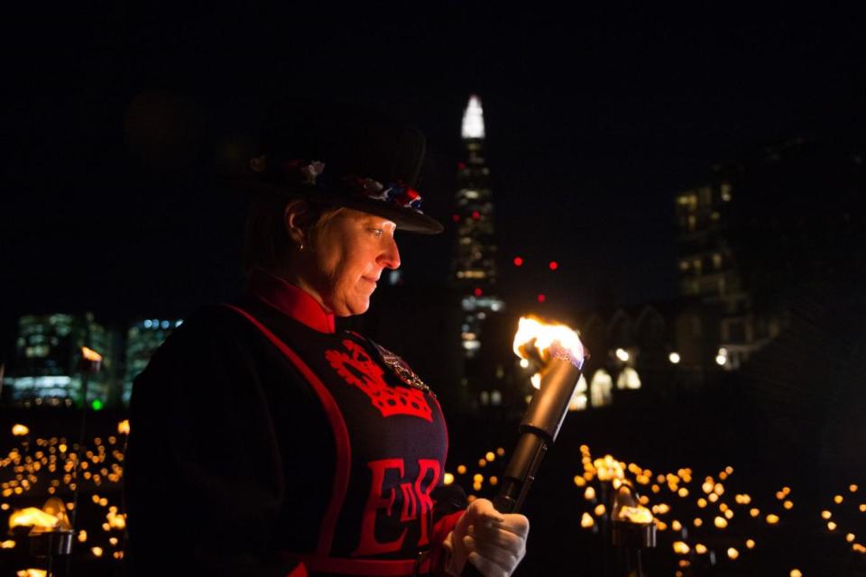 Moira Cameron Yeoman Warder of the Tower of London holds a torch during the service. (MoD)