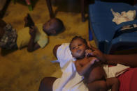 Veronique Louis holds her daughter as her son plays with a cell phone in her home in the Los Coquitos neighborhood of Santo Domingo, Dominican Republic, Sunday, Nov. 21, 2021. Earlier this month, Louis gave birth to her daughter at a hospital in Santo Domingo. She returned days later for further treatment because they botched the cesarean, but medical staff denied her care, according to her husband, Wilner Rafael. “They said they weren’t treating Blacks, and that Haitians aren’t people,” he said. (AP Photo/Matias Delacroix)