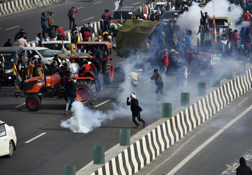 NEW DELHI, INDIA - JANUARY 26: Demonstrators being tear gassed by police at NH-24 near Akshardham during the farmers' tractor rally on Republic Day, on January 26, 2021 in New Delhi, India. Major scenes of chaos and mayhem at Delhi borders as groups of farmers allegedly broke barricades and police check posts and entered the national capital before permitted timings. Police used tear gas at Delhi's Mukarba Chowk to bring the groups under control. Clashes were also reported at ITO, Akshardham. Several rounds of talks between the government and protesting farmers have failed to resolve the impasse over the three farm laws. The kisan bodies, which have been protesting in the national capital for almost two months, demanding the repeal of three contentious farm laws have remained firm on their decision to hold a tractor rally on the occasion of Republic Day.(Photo by Sanjeev Verma/Hindustan Times via Getty Images)