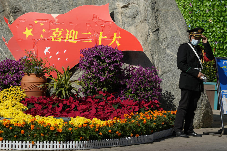 A security guard adjusts his capacity near a decoration promoting the upcoming 20th Party Congress to be held in Beijing, Sunday, Oct. 9, 2022. A meeting of the ruling Communist Party to install leaders gives President Xi Jinping, China's most influential figure in decades, a chance to stack the ranks with allies who share his vision of intensifying pervasive control over entrepreneurs and technology development. (AP Photo/Ng Han Guan)