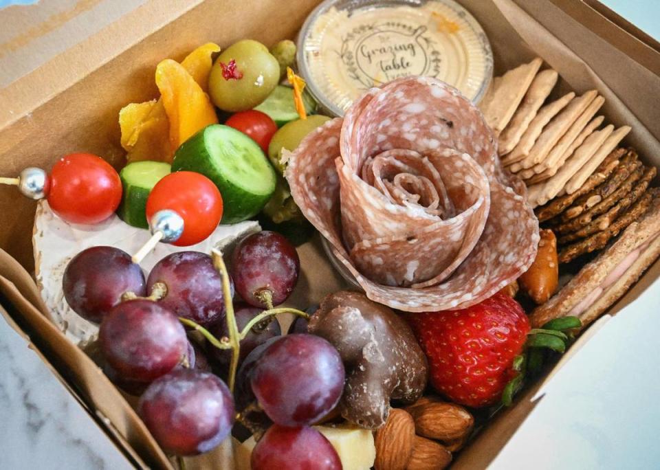 A grazing box featuring artisanal cheeses, cured meat, seasonal fruit, pickled items, dried fruit, nuts, and salami rose available at the Grazing Table Deli at their new location in northeast Fresno.