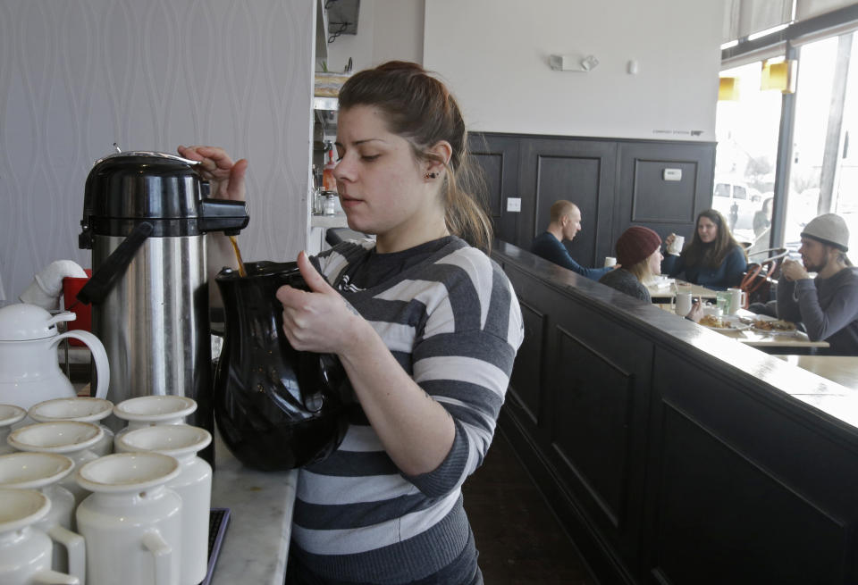 In this Tuesday, Jan. 28, 2014 photo, server Coleen Pratt fills a carafe with hot coffee at Bonbon Pastry and Cafe in Cleveland. Single-digit temperatures across the U.S. and record snowfalls in the Midwest since the beginning of January have put the freeze on businesses that rely on walk-ins and appointments. At the cafe in the city's Market Square district, the past weekend was especially slow with whiteout conditions making going outside unappealing for customers. (AP Photo)