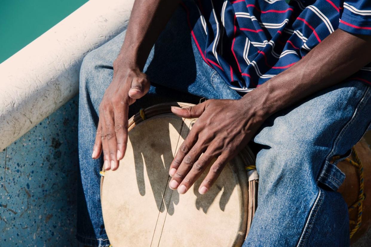 Garifuna man drumming on boat - Belize culture