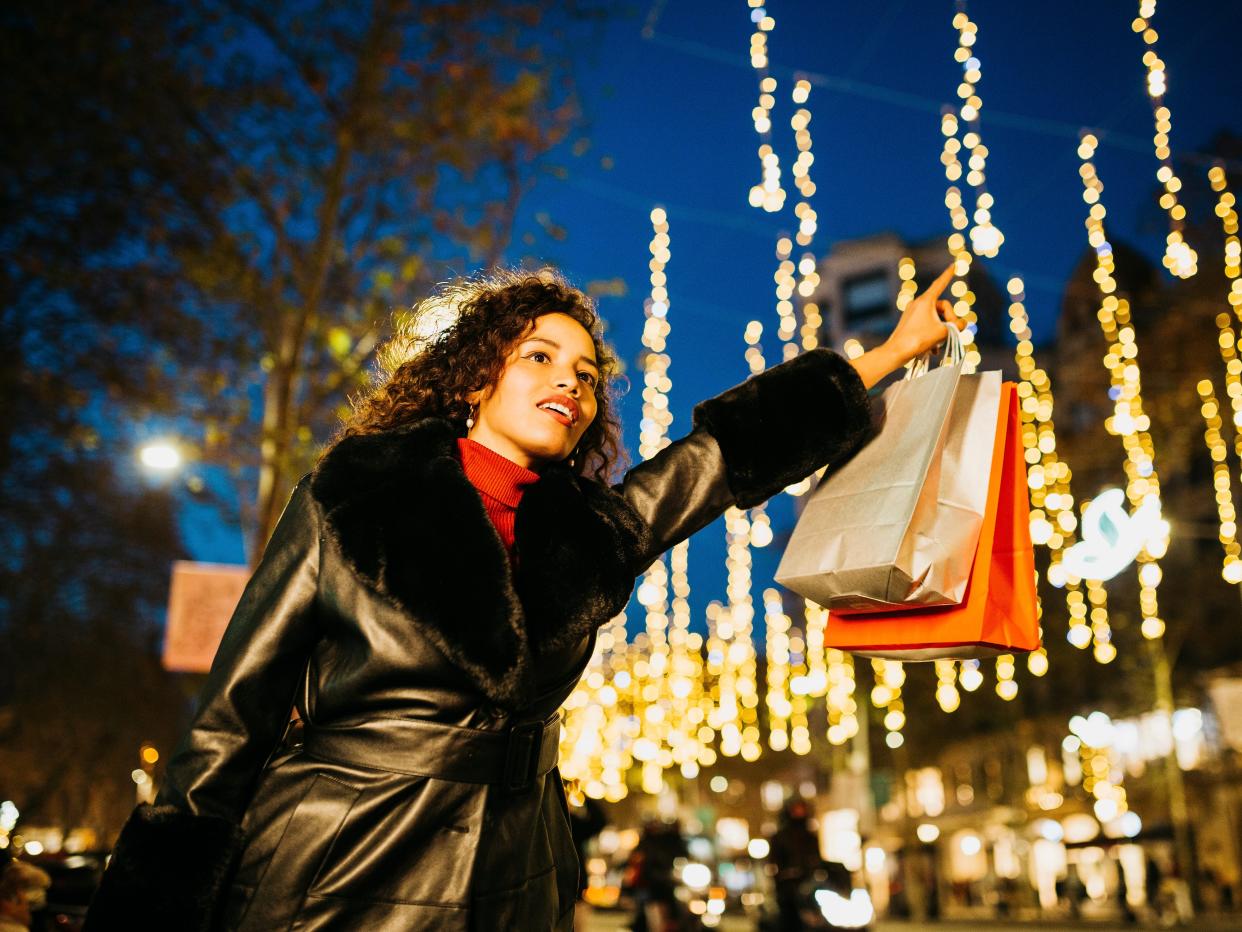 A woman hailing a cab with shopping bags at night