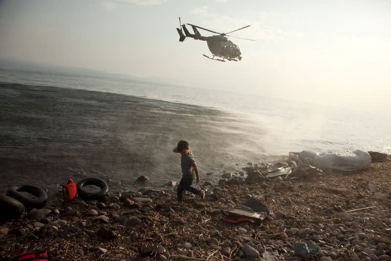 FILE PHOTO: A Frontex helicopter patrols over a Syrian child that has just arrived at a beach at the Greek island of Lesbos