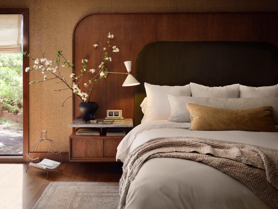 A bedroom with a wood panel and nightstand built into the wall and a bed sat against it.