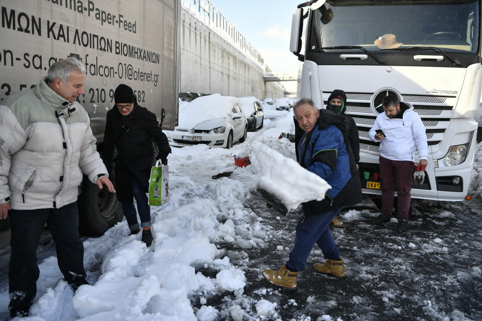 A track driver trapped for hours in a motorway shovel snow in Athens, on Tuesday, Jan. 25, 2022. Army and fire service teams were deployed late Monday to extract hundreds of motorists trapped for hours in snowed-in cars. A snowstorm of rare severity disrupted road and air traffic Monday in the Greek capital of Athens and neighboring Turkey's largest city of Istanbul, while most of Greece, including — unusually — several Aegean islands, and much of Turkey were blanketed by snow. (AP Photo/Michael Varaklas)