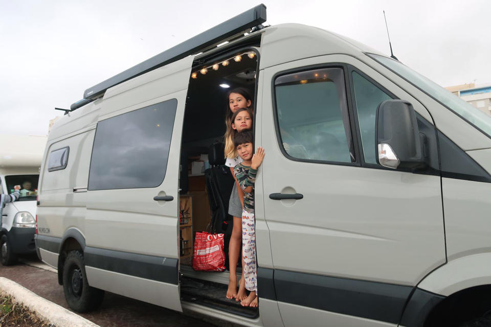 In this photo taken on Tuesday, March 24, 2020, stranded children tourists wait in their motor home as they queue in northern Morocco, near the Spanish enclave of Ceuta. Tourists were stranded in the region due to a lockdown and other strict measures taken by Moroccan authorities to limit the spread of the coronavirus. The new coronavirus causes mild or moderate symptoms for most people, but for some, especially older adults and people with existing health problems, it can cause more severe illness or death. (Andy McKettrick via AP)