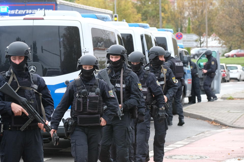 Police officers walk on a road in Halle, Germany, Wednesday, Oct. 9, 2019. One or more gunmen fired several shots on Wednesday in the German city of Halle. Police say a person has been arrested after a shooting that left two people dead. (Sebastian Willnow/dpa via AP)