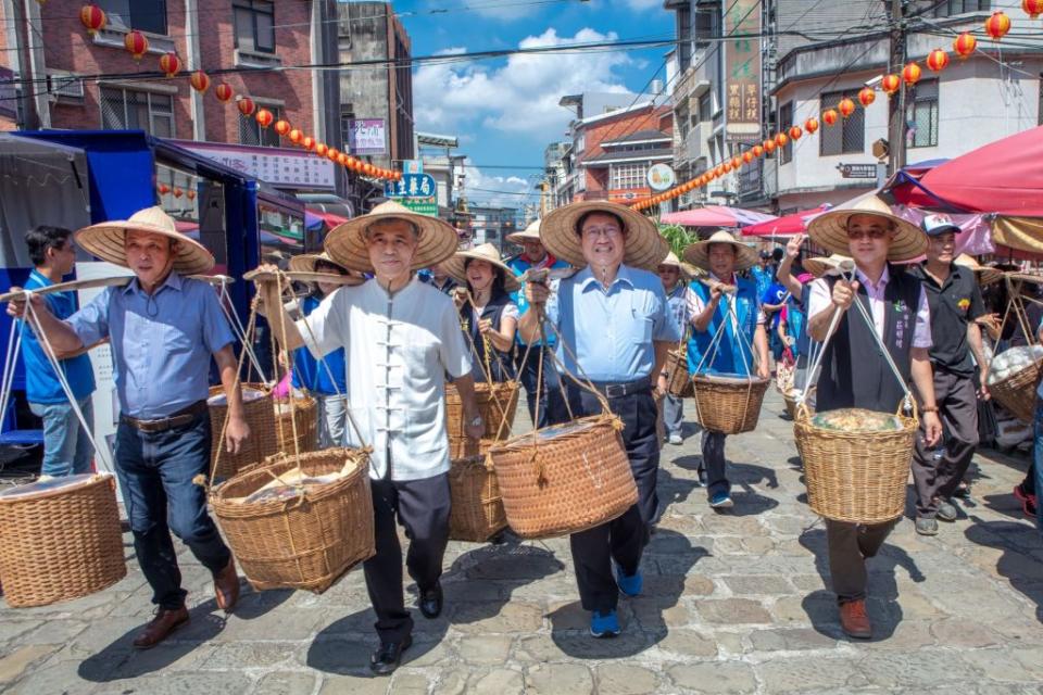 入選觀光局年曆照片—竹縣義民祭，由縣長楊文科（右二）及客委會副主委范佐銘（左二）共同挑擔奉飯，展現客家代代相傳對義民爺至高崇敬。（記者彭新茹翻攝）