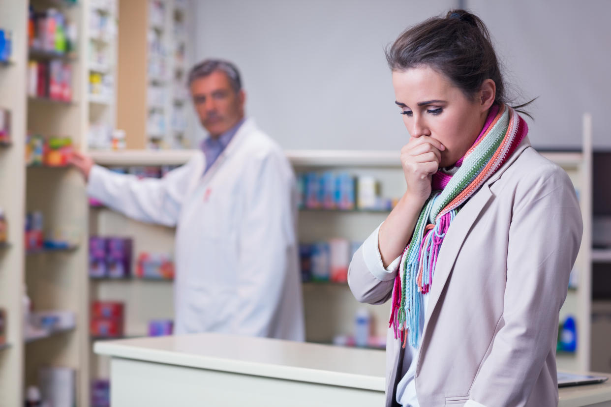 Portrait of a sick girl with scarf coughing in the pharmacy