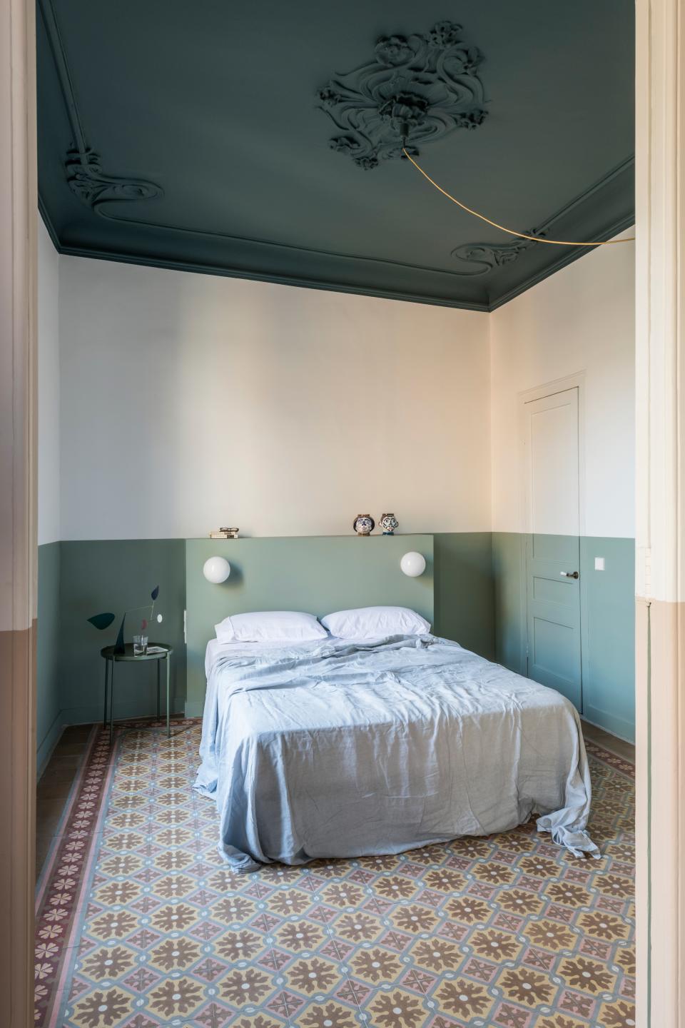 The master bedroom’s mint walls were meant to be a complementary departure from the terra-cotta shade of the shared spaces. In this case, the color almost works as a headboard that encompasses shelving and globe sconces.