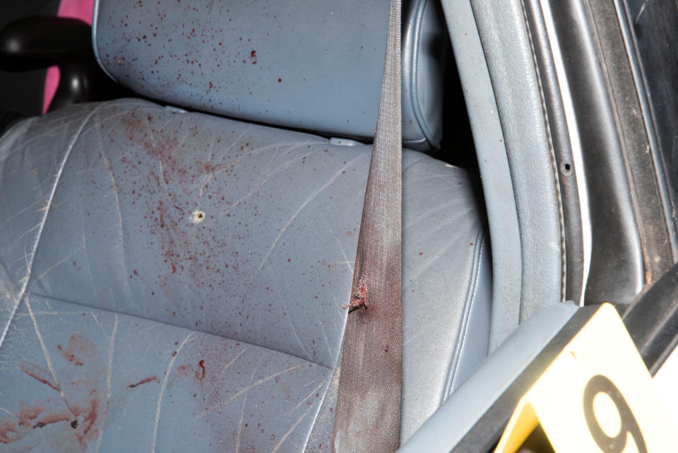 Bloodstains and bullet holes are seen in the front seat.