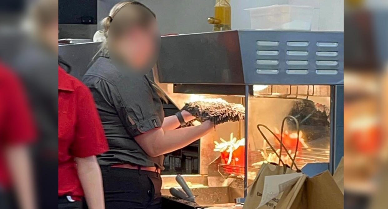 A McDonald's employee is seen holding the head of a mop to a heat lamp above fries. Source: Facebook