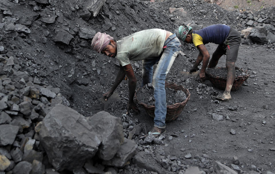 In this Oct. 23, 2019, photo, laborers fill baskets with coal before loading it into trucks for transportation in the village of Godhar in Jharia,, a remote corner of eastern Jharkhand state, India. The fires started in coal pits in eastern India in 1916. More than a century later, they are still spewing flames and clouds of poisonous fumes into the air, forcing residents to brave sizzling temperatures, deadly sinkholes and toxic gases. (AP Photo/Aijaz Rahi)