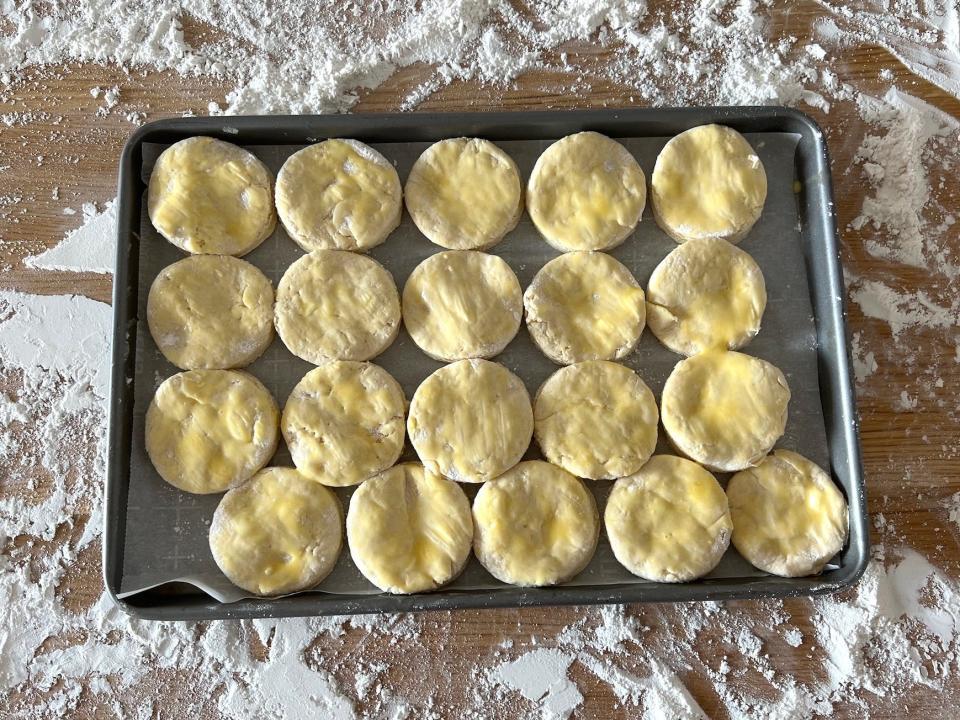 A tray full of biscuits with an egg wash on top of it.