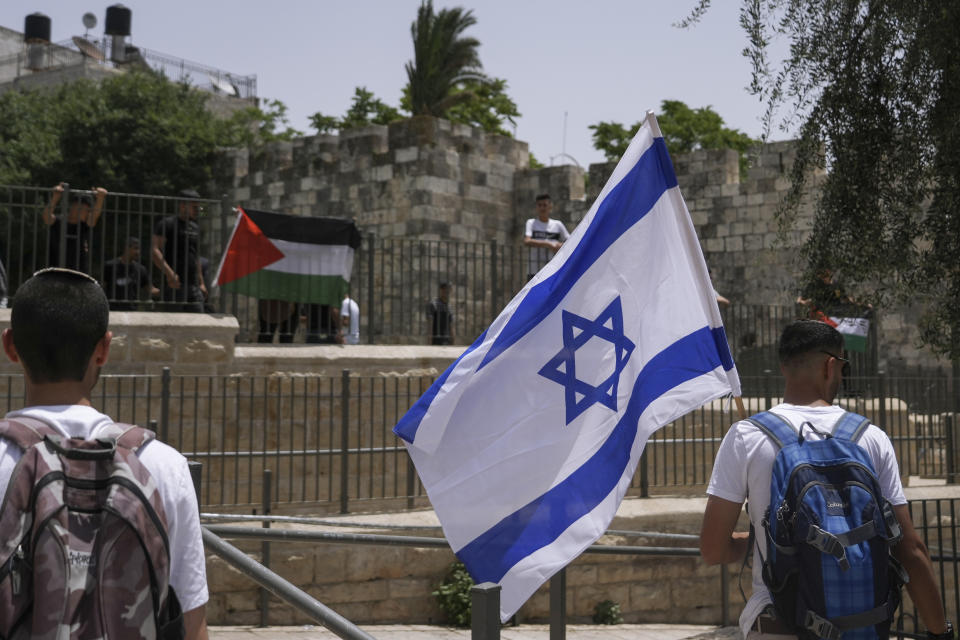 Palestinians and Israelis wave their national flags outside Jerusalem's Old City as Israelis mark Jerusalem Day, an Israeli holiday celebrating the capture of the Old City during the 1967 Mideast war. Sunday, May 29, 2022. Israel claims all of Jerusalem as its capital. But Palestinians, who seek east Jerusalem as the capital of a future state, see the march as a provocation. Last year, the parade helped trigger an 11-day war between Israel and Gaza militants. (AP Photo/Mahmoud Illean)