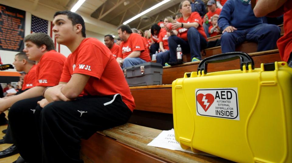 An AED sits on the team bench as an injured player and best friend of Wes Leonard, Xavier Grigg sits and watches with others as their team warms up for their home game against Saugatuck on Jan 6, 2012.