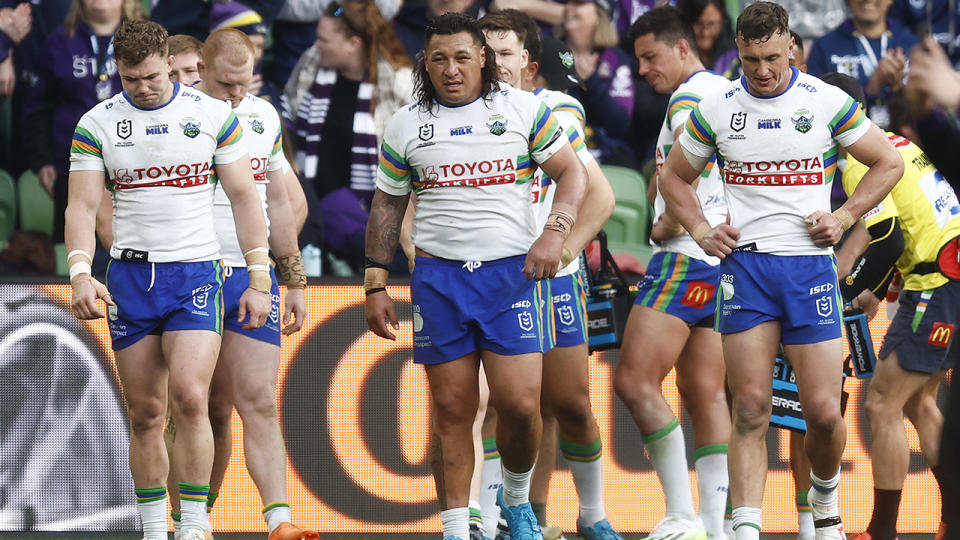 Canberra Raiders players look down at the ground after a try was scored by the Melbourne Storm.