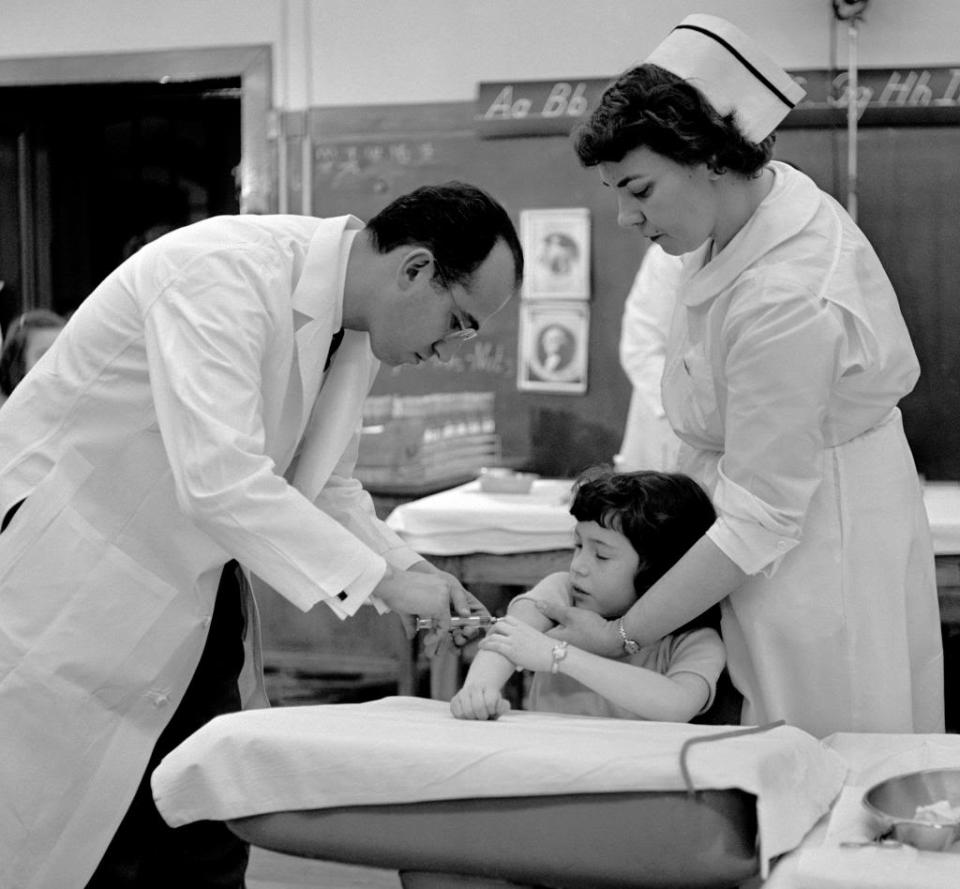 Dr. Jonas Salk gives a vaccine injection to a girl at Colfax Elementary School in Pittsburgh in 1954.