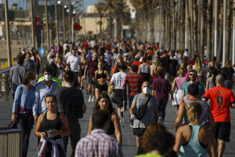 People exercise on a seafront promenade in this photo taken with a telephoto lens in Barcelona, Spain, Saturday, May 2, 2020. Spaniards have filled the streets of the country to do exercise for the first time after seven weeks of confinement in their homes to fight the coronavirus pandemic. People ran, walked, or rode bicycles under a brilliant sunny sky in Barcelona on Saturday, where many flocked to the maritime promenade to get as close as possible to the still off-limits beach. (AP Photo/Emilio Morenatti)