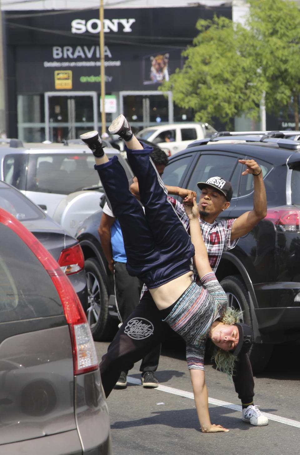 In this Dec. 12, 2018 photo, Venezuelans Maria Molina, upside down, and Miguel Angel Flores breakdance for tips from commuters with in Lima, Peru. Most Venezuelan migrants head to neighboring Colombia, overwhelming border towns, while Peru is the second-most-common destination. (AP Photo/Cesar Olmos)